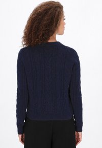 Suéter de punto de cable azul marino con mangas largas, dobladillo acanalado y patrón texturizado, con un escote redondo y un corte relajado.