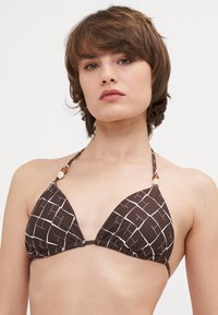 Rjav trikotni bikini zgornji del z belim mrežastim vzorcem, ki ima nastavljive zaveze in okrasne kroglice na trakcih. Narejen iz mehke tkanine.