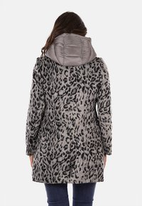 Abrigo de estampado de leopardo con una capa exterior texturizada en gris, una capucha brillante en gris y una silueta ajustada. Presenta mangas largas y un corte recto.