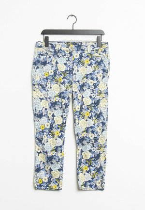 Pantaloni a stampa floreale con base blu navy, caratterizzati da grandi fiori bianchi e gialli. Vestibilità slim con una texture liscia, esposti su una gruccia nera.