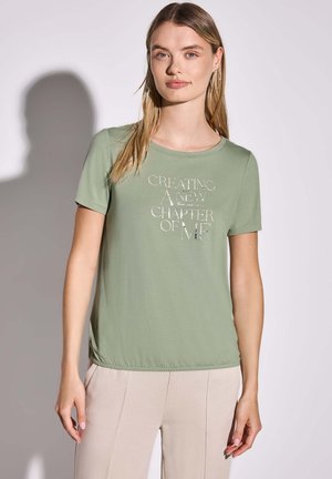 T-shirt vert clair à manches courtes en tissu doux, avec un design texte imprimé en blanc qui dit "CRÉER UN NOUVEAU CHAPITRE DE MOI."
