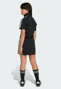 Czarny sportowy strój z krótkimi rękawami, dopasowaną górą i spódnicą. Posiada białe paski na ramionach i bokach. Noszony z wysokimi skarpetkami sięgającymi kolan.