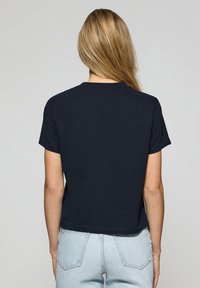 T-shirt bleu marine à manches courtes avec un col rond, présentant une coupe décontractée et une texture en coton lisse. La vue arrière montre un design simple.