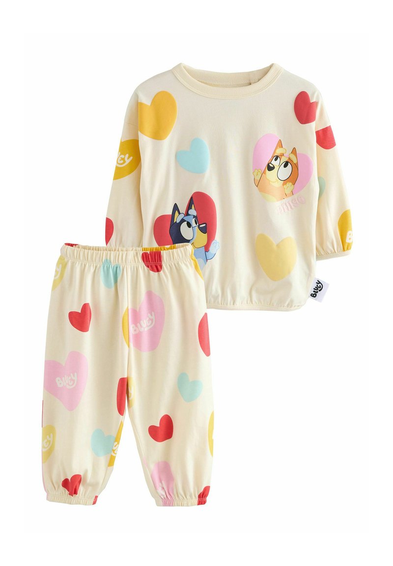 Set di pigiami per bambini composto da due pezzi, con una maglietta color crema e pantaloni abbinati. Entrambi presentano motivi a cuori colorati e stampe di personaggi dei cartoni.