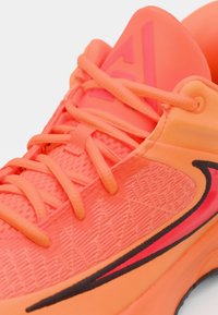 Athletic shoe in bright orange, featuring a textured mesh upper, flat laces, and a black accent stripe along the sole.