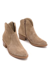 Para beżowych zamszowych botków za kostkę z bocznymi suwakami i niskimi obcasami na białym tle.