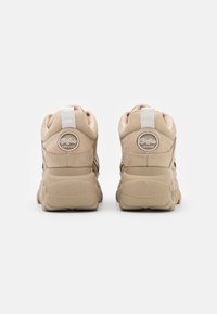 Baskets montantes beiges avec une semelle texturée, un upper en cuir lisse, des accents de logo sur le talon et un onglet blanc à l'arrière.