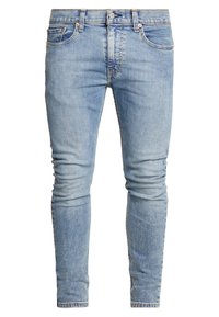 Jeans de mezclilla ajustados de color azul claro con bolsillos frontales, trabillas, cierre de botón y un ligero desgastado en los muslos y las rodillas.