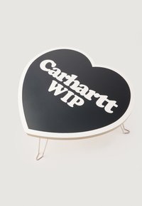 Tavolo a forma di cuore con superficie nera e logo "Carhartt WIP" bianco. Presenta un bordo in legno chiaro e gambe in metallo per il supporto.