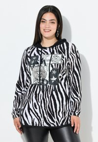Schwarz-weiße, zebra gestreifte Kapuzenjacke mit einem Frontdesign, das Leopard-Bilder und Sterne zeigt. Lange Ärmel, mit Kordelzug, gerippte Bündchen.