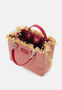 Czerwono-biała torba w paski z frędzlami ze słomy, skórzanymi uchwytami i srebrnymi elementami. Wnętrze wykończone czarną podszewką i zapięciem na zatrzask.