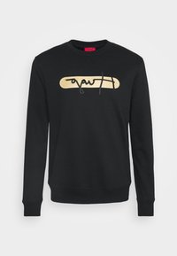 Sudadera negra de tejido suave, con un logo rectangular dorado con letras negras en el pecho y puños acanalados.