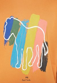 Camisa de algodón naranja con un contorno blanco de un caballo, superpuesto con patrones de pinceladas en azul, verde, amarillo, rosa y negro.
