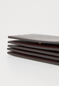 Dark burgundy leather wallet with a textured finish, featuring multiple card slots and a stitched border, curved top edge, and a slim profile.