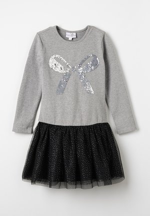 Grijze lange mouwen jurk met een pailletten strikdesign, met een zwarte tule rok versierd met witte stippen. Zachte stoftextuur.