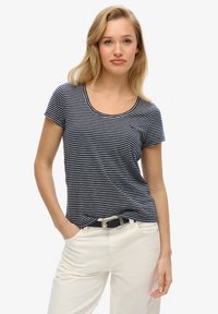 Camiseta de rayas azul marino y blanca de manga corta con escote redondeado, de tela suave, combinada con pantalones blancos, con un cinturón negro y una hebilla plateada.