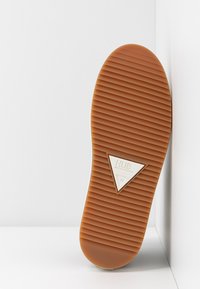 Brown rubber sole with vertical grooves, featuring a triangular white accent with "HUB" logo. Smooth edges and rounded shape.