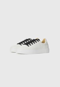 Hvite lær sneakers med svarte lisser, teksturert overflate, forsterket tå og tykk hvit såle, med metalløyler for feste av lisser.