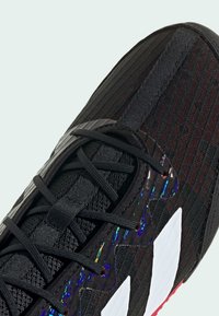 Black athletic shoe featuring a textured fabric upper, sleek design, reflective accents, and white logo detail on the side.