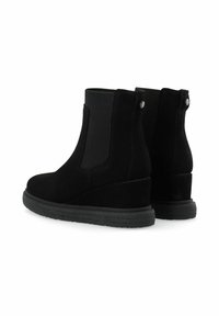 Botas de tobillo de ante negro con paneles laterales elásticos, tacón en cuña y punta redonda. Textura suave con acentos de metal en el tacón.