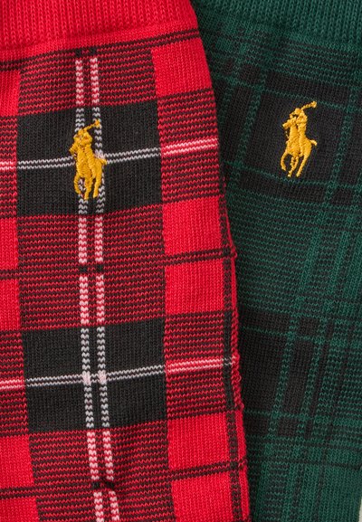 Gros plan d'un tissu tricoté à carreaux rouges et verts avec des logos brodés jaunes de joueurs de polo sur chaque.
