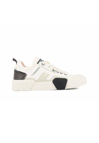 White sneakers with a textured rubber sole, featuring black and gray accents, round laces, and branding on the side and tongue.