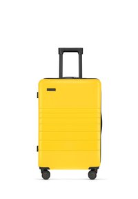 Yellow hard-shell suitcase with textured stripes, retractable black handle, and four black wheels for easy mobility.