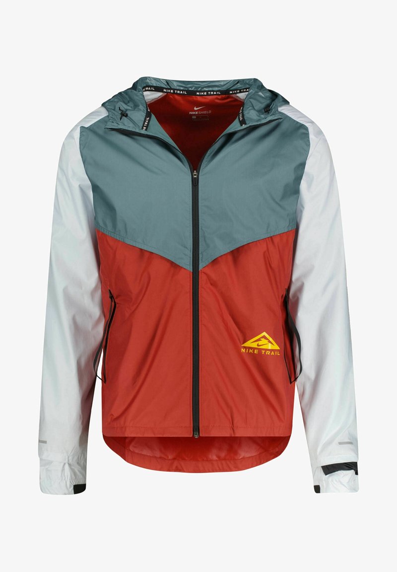 Nike Trail takki, jossa on punainen runko, teal-värinen yläosa ja valkoiset hihat. Huomattava keltainen logo oikeassa alakulmassa. Kevyt, vetoketjullinen malli.