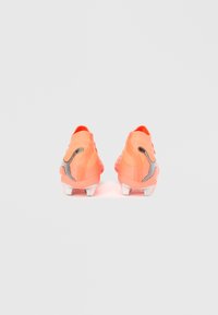 Jalkapallokengät kirkkaan korallin värisinä, joissa on teksturoitu yläosa, mustat yksityiskohdat ja valkoinen pohja, suunniteltu pitoon ja suorituskykyyn.