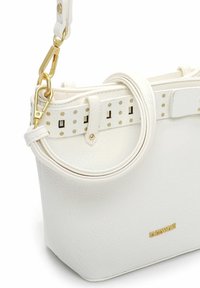 Valge nahast käekott struktureeritud kujuga, kuldsete detailidega ja eemaldatava rihmaga, millel on perforatsiooniga disain.