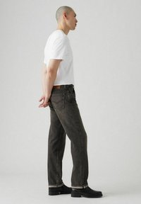 Zwarte denim jeans met een rechte snit, voorzien van een middelhoge wassing en subtiele vervaging, gecombineerd met een eenvoudige witte t-shirt en zwarte enkellaarsjes.