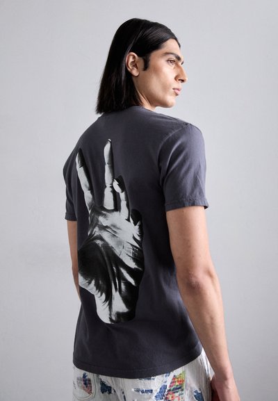 Graphic t-shirt in dark gray cotton. Features a large black and white handprint design on the back. Short sleeves and crew neck.