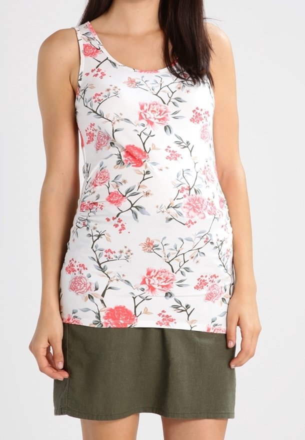 Top sin mangas floral con base blanca que presenta flores en tonos rosa y rojo. Combinado con una falda corta de un verde oscuro, el tejido parece suave y ligero.