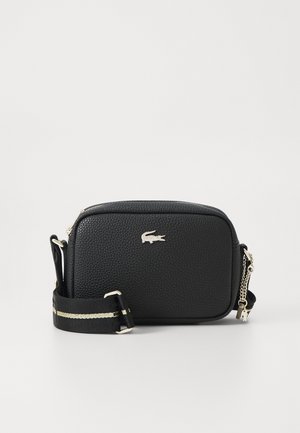 Black textured crossbody bag with silver crocodile logo, adjustable black strap with beige stripe, and silver zipper with chain pull.