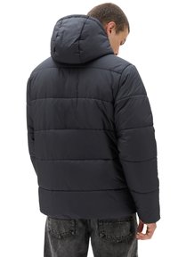 Kurtka puchowa w ciemnoszarym kolorze, z kapturem, pikowanym wzorem i długimi rękawami. Tył ma poziome szwy i minimalną ilość elementów metalowych.