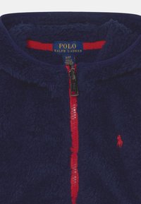 Marintröja i fleece med dragkedja, röd dragkedja och detaljer; har en Polo-logga broderad på bröstet; mjukt, texturerat tyg.