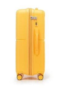 Valigia rigida gialla con doppia cerniera, lucchetto a combinazione e maniglia superiore. Quattro ruote per la mobilità, texture liscia con scanalature orizzontali.