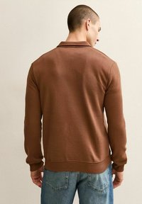 Braun sweatshirt mit langen Ärmeln, gerippten Bündchen und Kragen. Aus weichem Material gefertigt, hat einen geraden Saum und eine lässige Passform.