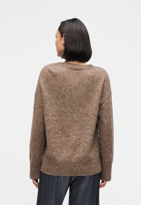 Καφέ πλεκτό πουλόβερ με χαλαρή εφαρμογή, ριμπ μανσέτες και τελείωμα, με απαλό ύφασμα και διακριτικό μαρλε μοτίβο.