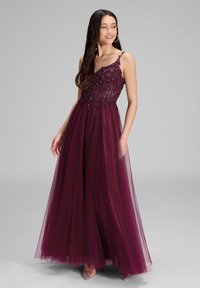 Bordowa wieczorowa suknia z dopasowaną, zdobioną górą i zwiewnym tiulowym dołem. Posiada cienkie ramiączka oraz wyszukane detale z koralików.