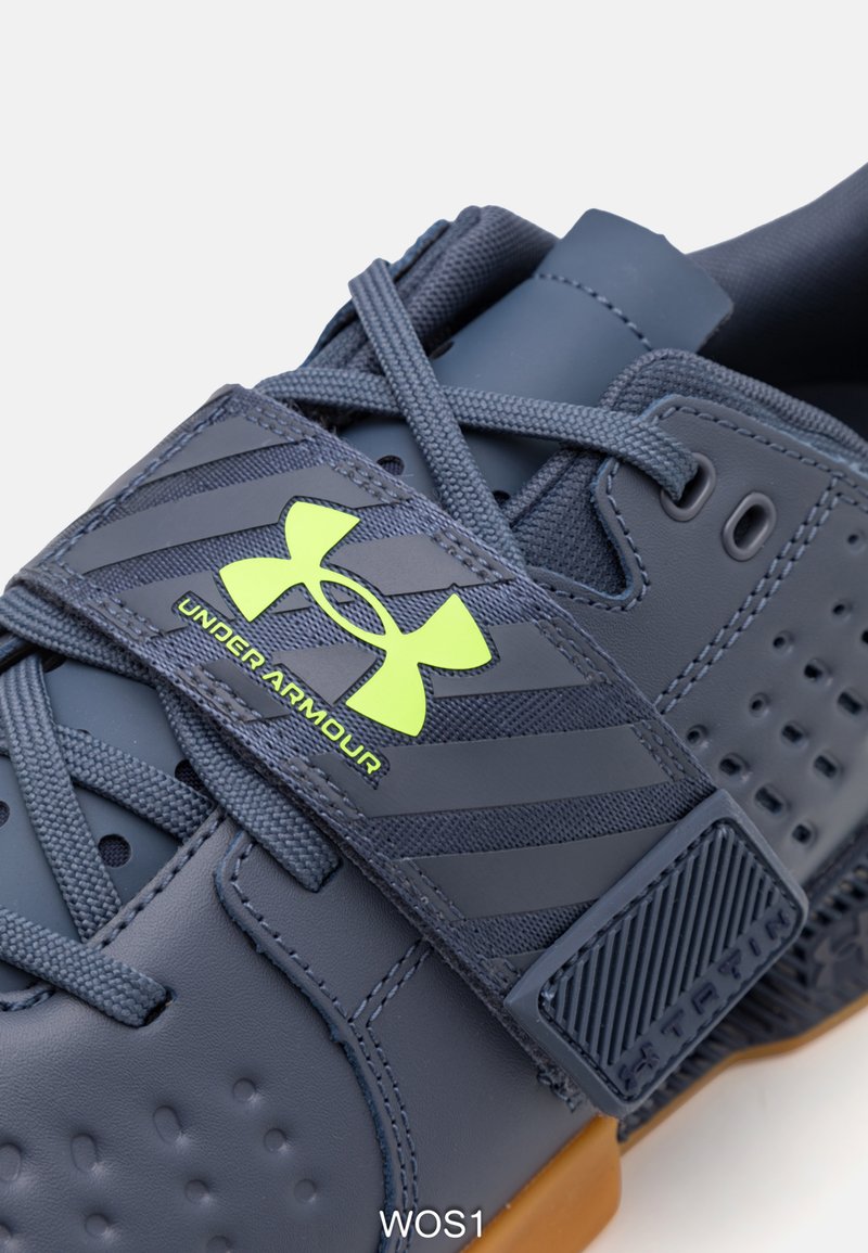 Dunkelblaue Sportschuhe mit Gummisohle, Mesh-Akzenten und durchlochten Details. Verfügt über einen Klettverschluss mit einem grünen Logo.