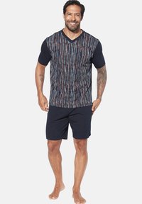 Navy Baumwoll-T-Shirt mit mehrfarbigen vertikalen Streifen; V-Ausschnitt-Design. Kombiniert mit dunklen Shorts, die einen lässigen, bequemen Look zeigen.