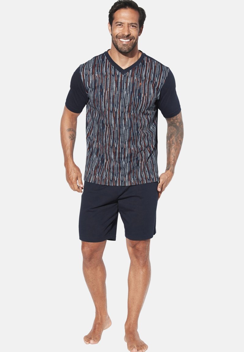 Navy Baumwoll-T-Shirt mit mehrfarbigen vertikalen Streifen; V-Ausschnitt-Design. Kombiniert mit dunklen Shorts, die einen lässigen, bequemen Look zeigen.