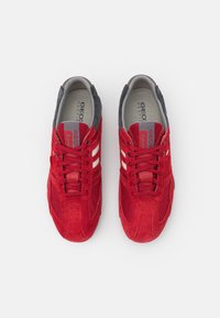 Scarpe sportive rosse caratterizzate da un mix di materiali scamosciati e in mesh, design a punta rotonda e dettagli bianchi sui lati.