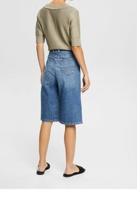 Denim culottes vaalealla pesulla, joissa on korkea vyötärö, kaksi takataskua ja raaka helma. Yhdistettynä vaaleaan neulepaitaan ja litteisiin sandaaleihin.