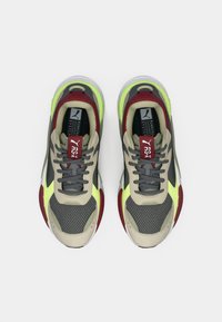 Lightweight athletic shoes in beige, gray, and red with mesh textures and bright yellow accents. Feature flat laces and cushioned soles.