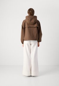 Braun karierte Jacke mit Kapuze, lässiger Schnitt und gerafften Ärmeln, kombiniert mit weiten weißen Hosen. Minimalistisches Design ohne Verzierungen.