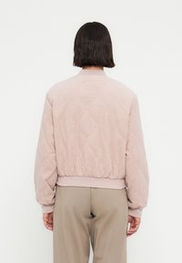 Κουμπωτό μπουφάν bomber σε απαλό ροζ χρώμα, με ριμπ γιακά και μανσέτες, ελαστική μέση και λεία υφή. Απλός και λειτουργικός σχεδιασμός.