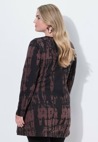Dlouhá tunika v černé barvě s vínovým tie-dye vzorem, s kulatým výstřihem a volným střihem, který končí v polovině stehna.