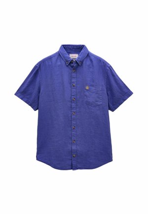 Hellblaues Hemd mit kurzen Ärmeln und Knöpfen, mit Vordertasche und braunen Knöpfen, aus strukturiertem Stoff, Kragen auf weißem Hintergrund zugeknöpft.